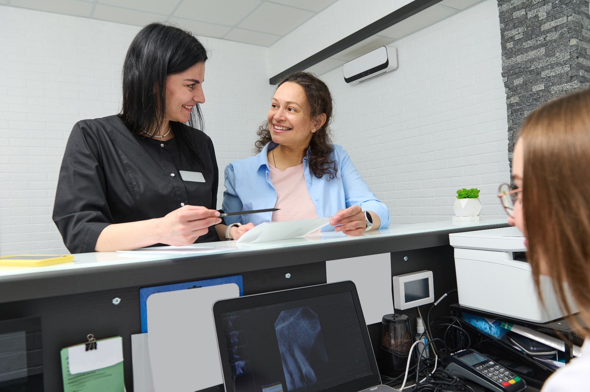 Two front office team members welcoming a patient at the practice reception desk