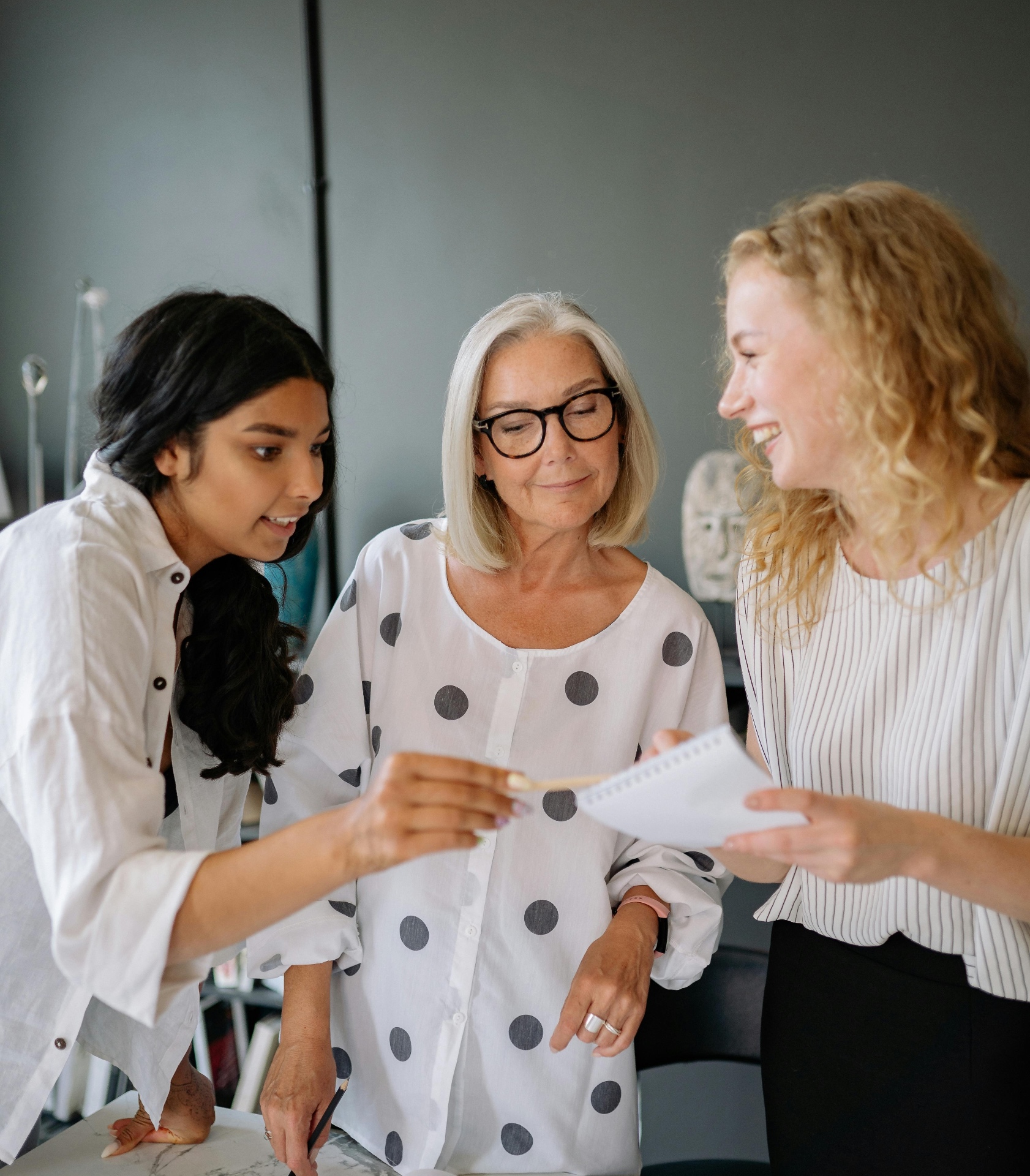 Three women of different generations collaborating around a notebook